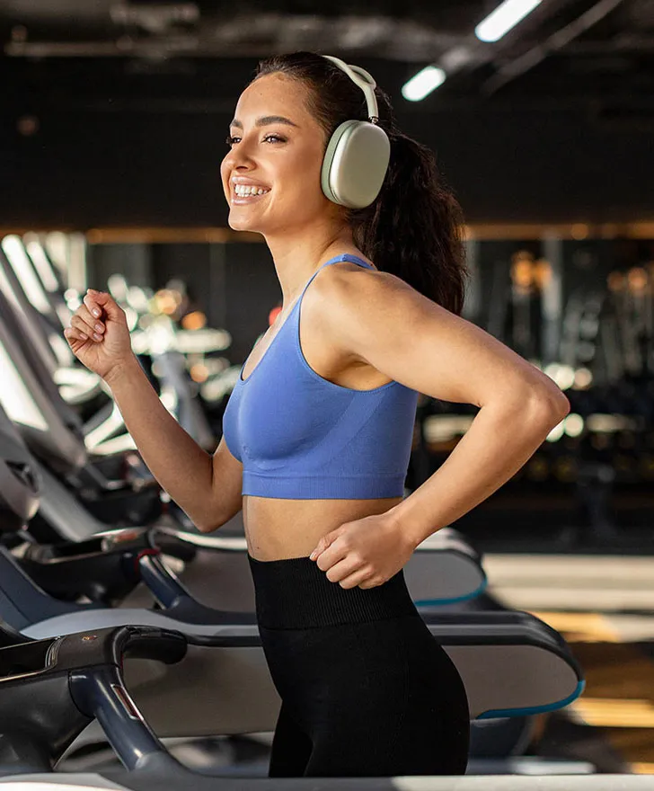 Smiling woman in a blue sports top doing a cardio workout in a gym
